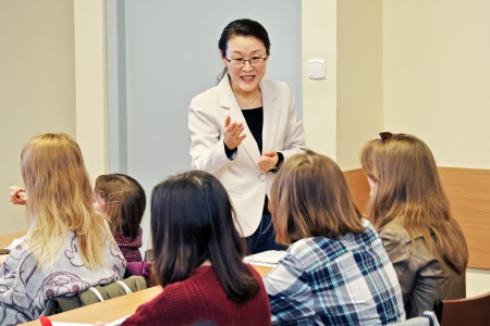 Na pierwszym planie prowadząca zajęcia na tle monitora interaktywnego podczas zajęć. Kliknij, aby powiększyć zdjęcie.